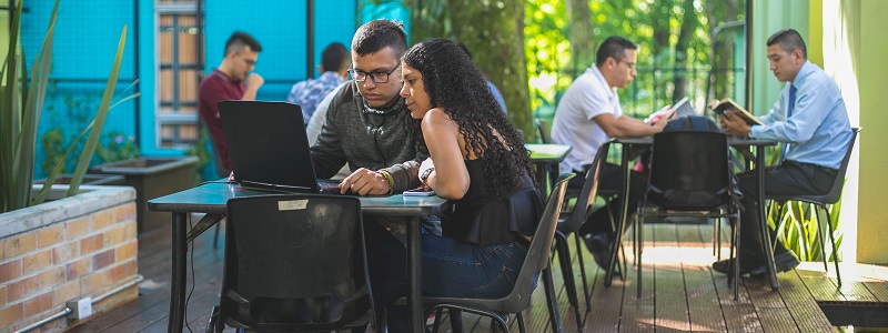 Imagen estudiantes sentados en las mesas de la biblioteca de Unibagué